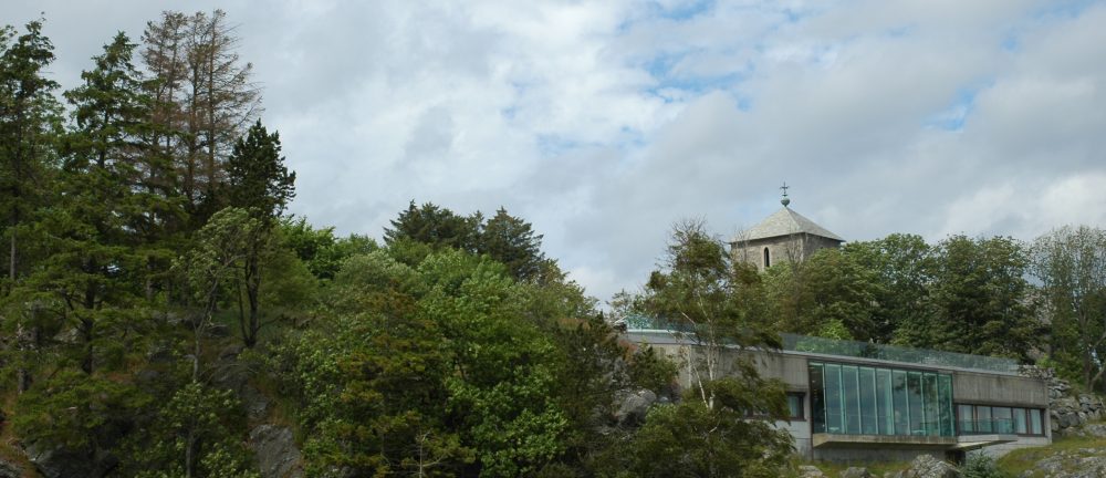 Avaldsnes, juli 2010. Historiesenteret, kirketrnet og skogen. Til venstre i bildet str de tre dende granene som ble ringbarket vren 2009.